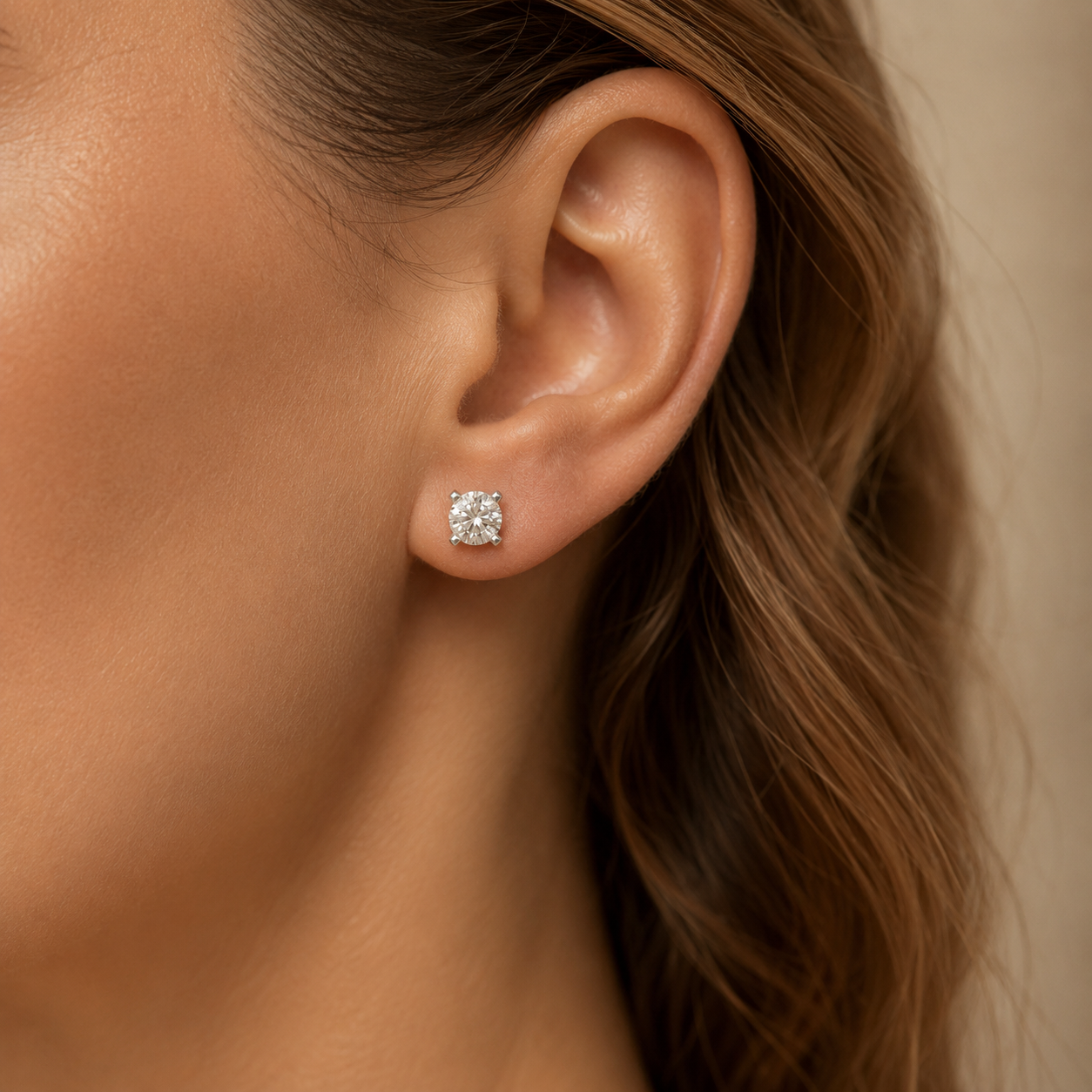 Close-up lifestyle view of a round four-prong lab grown diamond stud earring worn on the ear